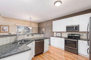 Columbus OH Kitchen with grey granite counters, fresh white cabinets, stainless steel appliances, and hardwood floors.
