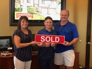Westerville family holding a Sold sign and standing in front of home sold by Realtor Rita Boswell